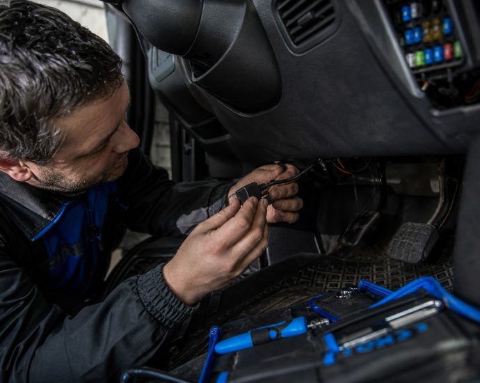 Technik montuje GPS jednotku do vozidla